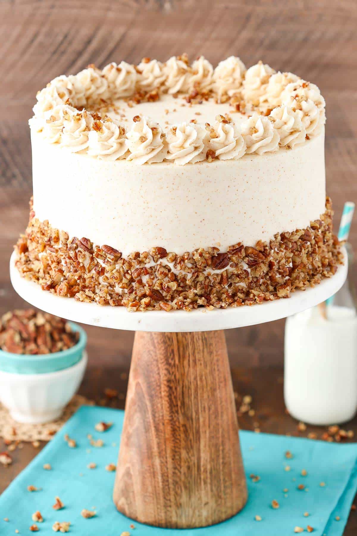 A browned butter pecan layer cake on a tall cake stand.