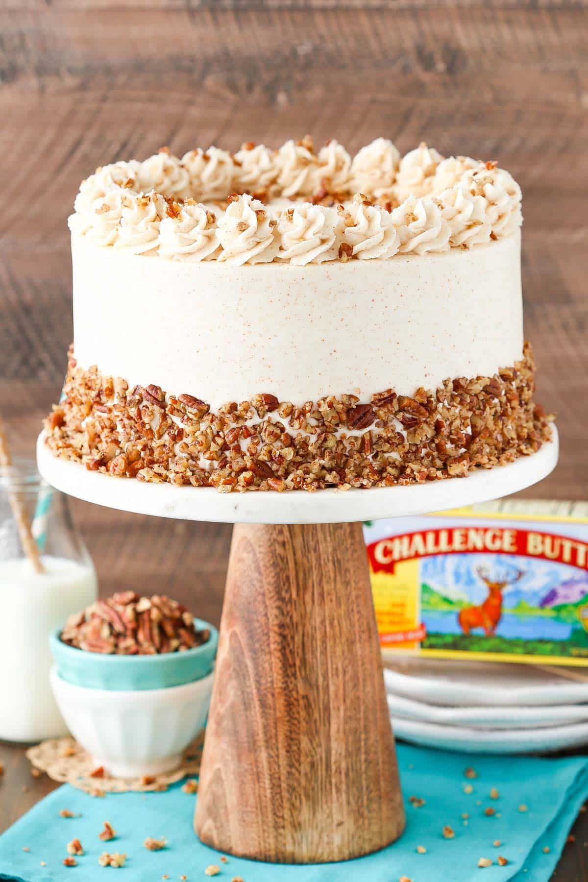 A browned butter pecan layer cake on a tall cake stand.
