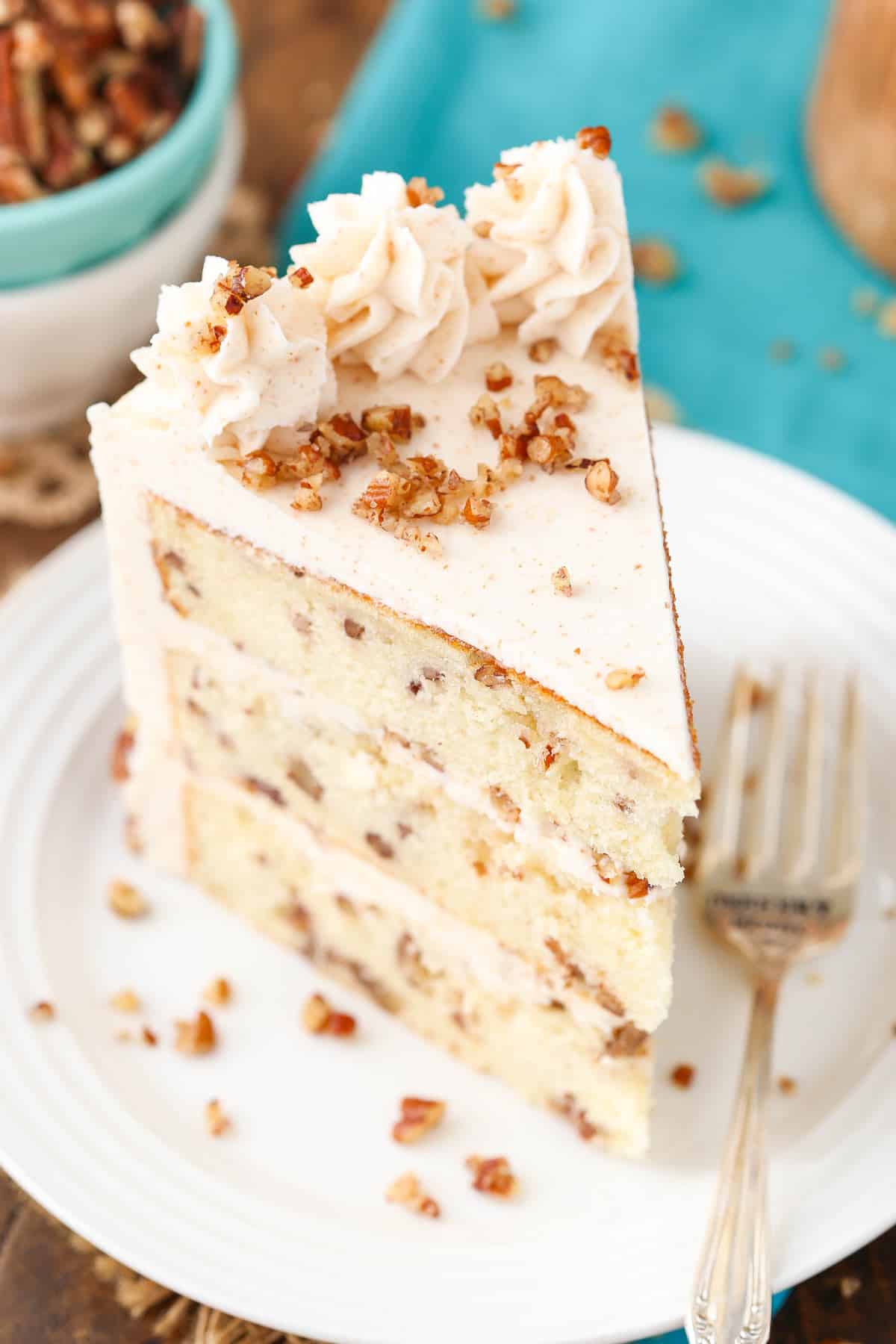 Top view of a slice of browned butter pecan layer cake on a white plate.