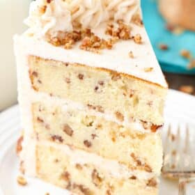 A tall slice of browned butter pecan layer cake on a white plate.