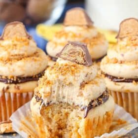 Close up of a Butterfinger Cupcake with a bite removed with its wrapper pulled down.
