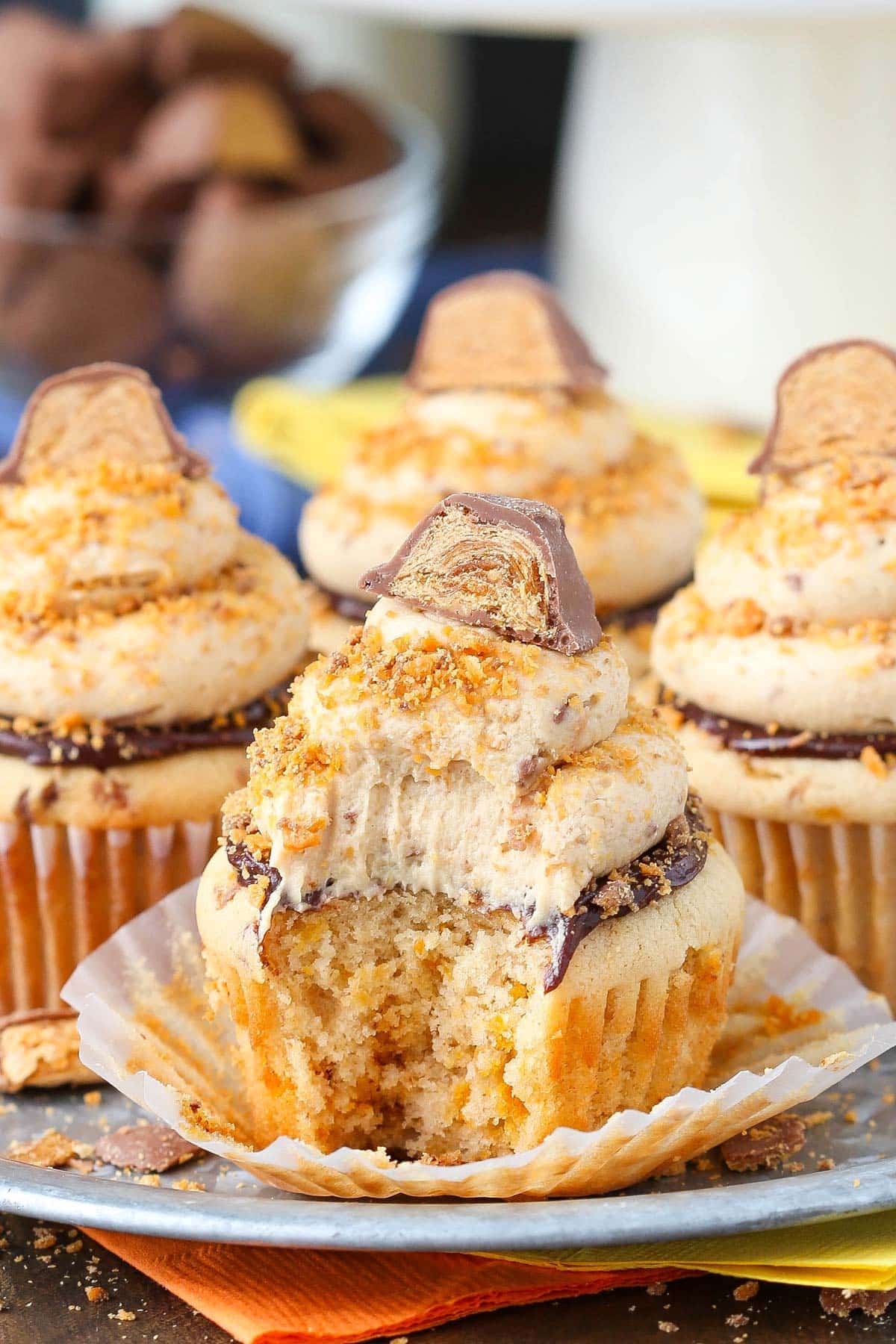 Close up of a Butterfinger Cupcake with a bite removed with its wrapper pulled down.