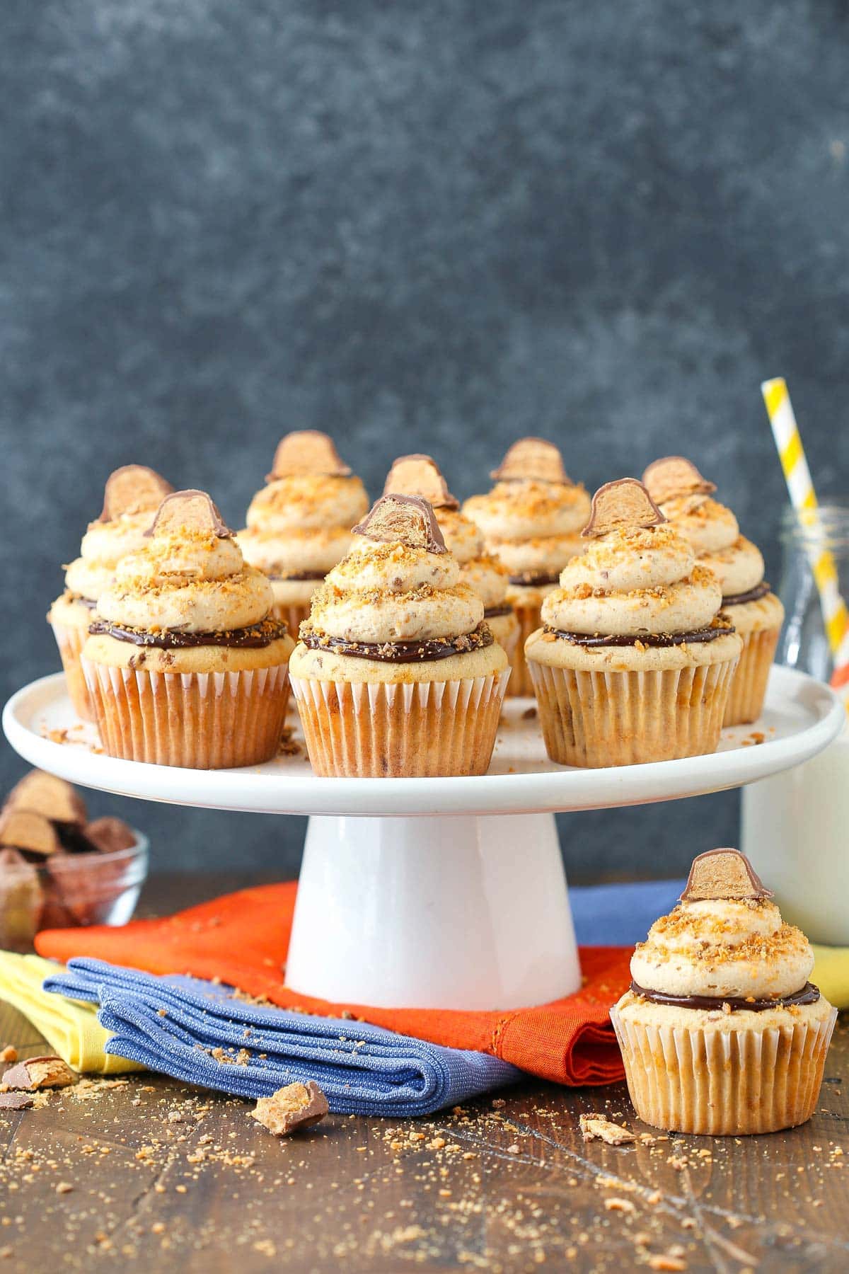 A white cake stand with several Butterfinger Cupcakes on top.