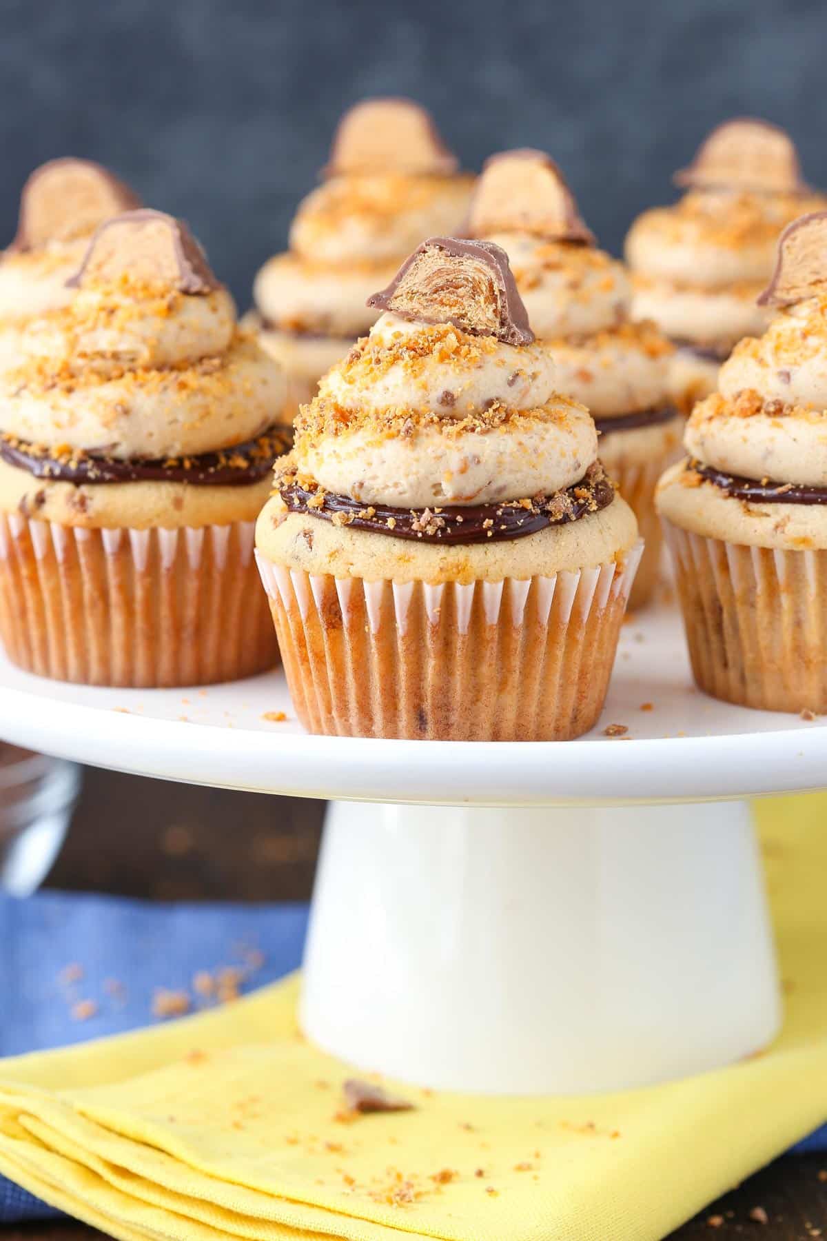 Close up of Butterfinger Cupcakes on a white cake stand.