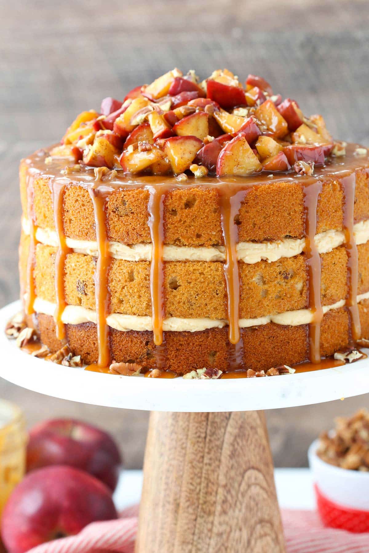 Close up of a caramel apple pecan layer cake on a white cake stand.