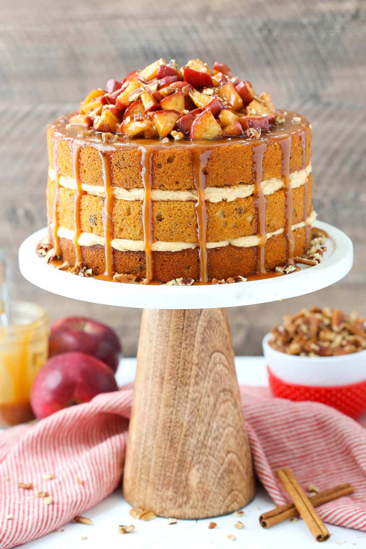 A caramel apple pecan layer cake on a white cake stand.