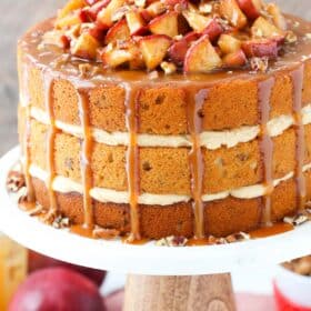 A caramel apple pecan layer cake on a white cake stand.