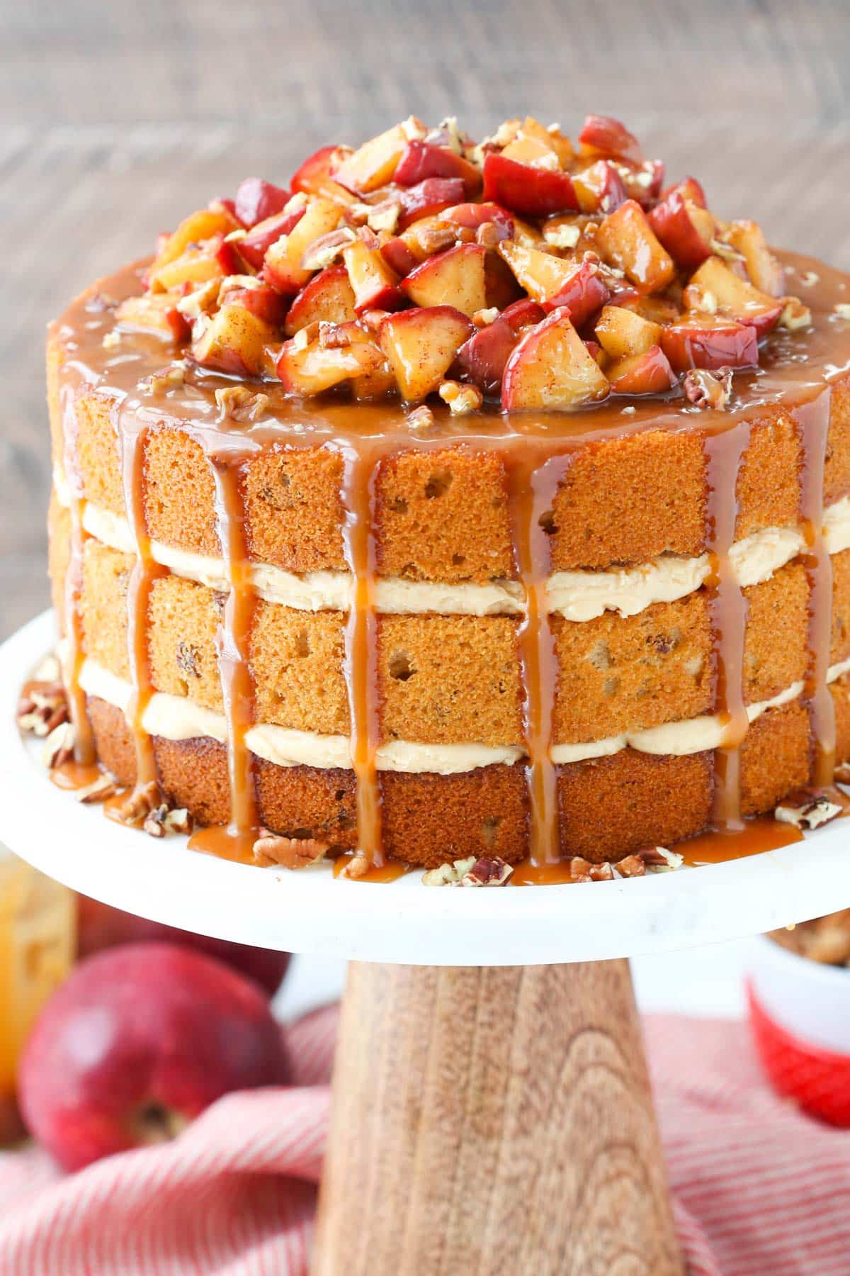 A caramel apple pecan layer cake on a white cake stand.