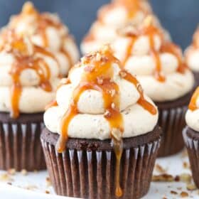 Close up of chocolate turtle cupcakes on a white cake stand.