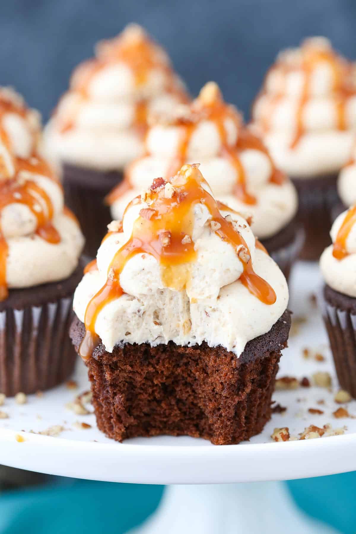 Close up of a chocolate turtle cupcake with a bite removed.