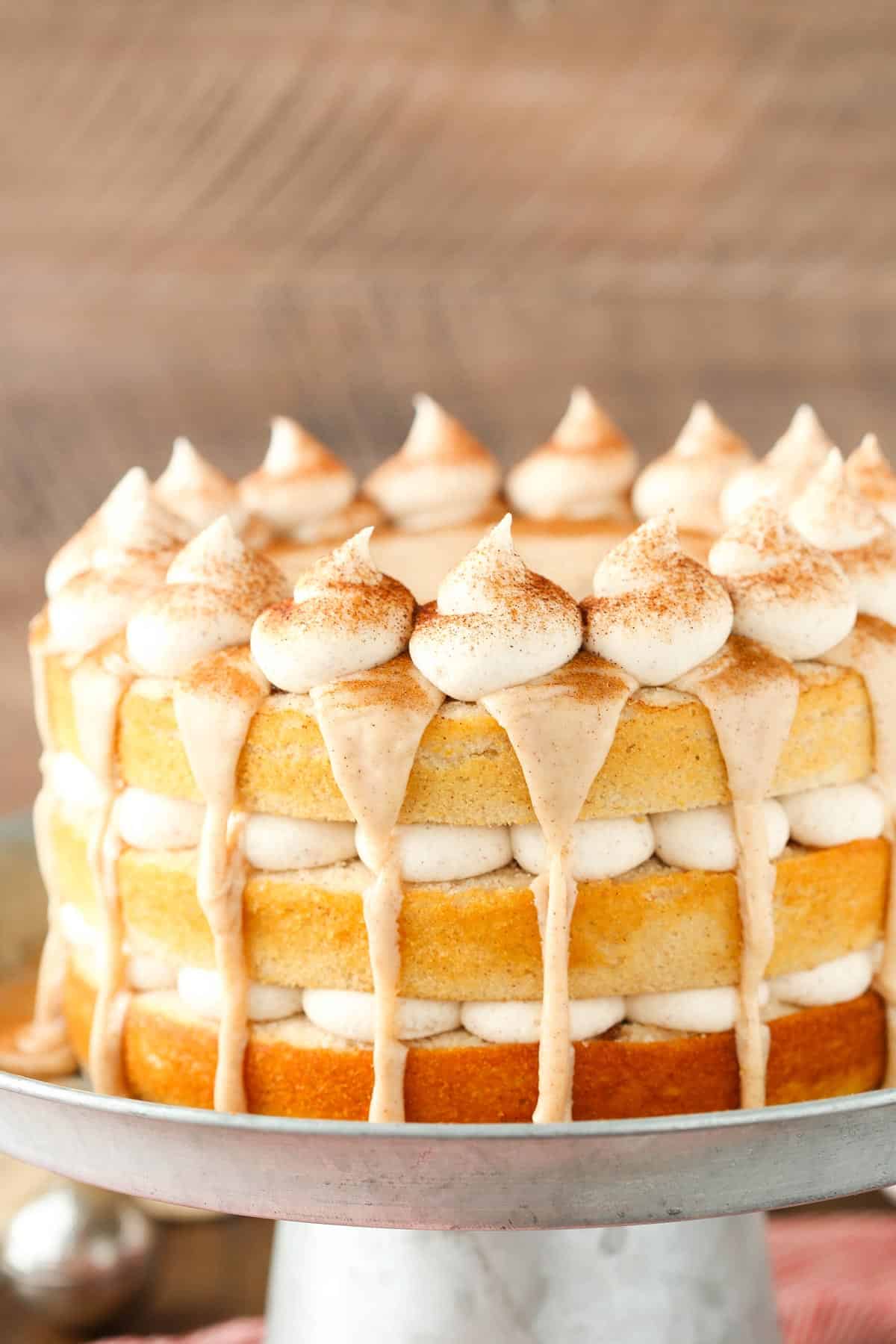 Close up of a cinnamon roll layer cake on a silver stand.
