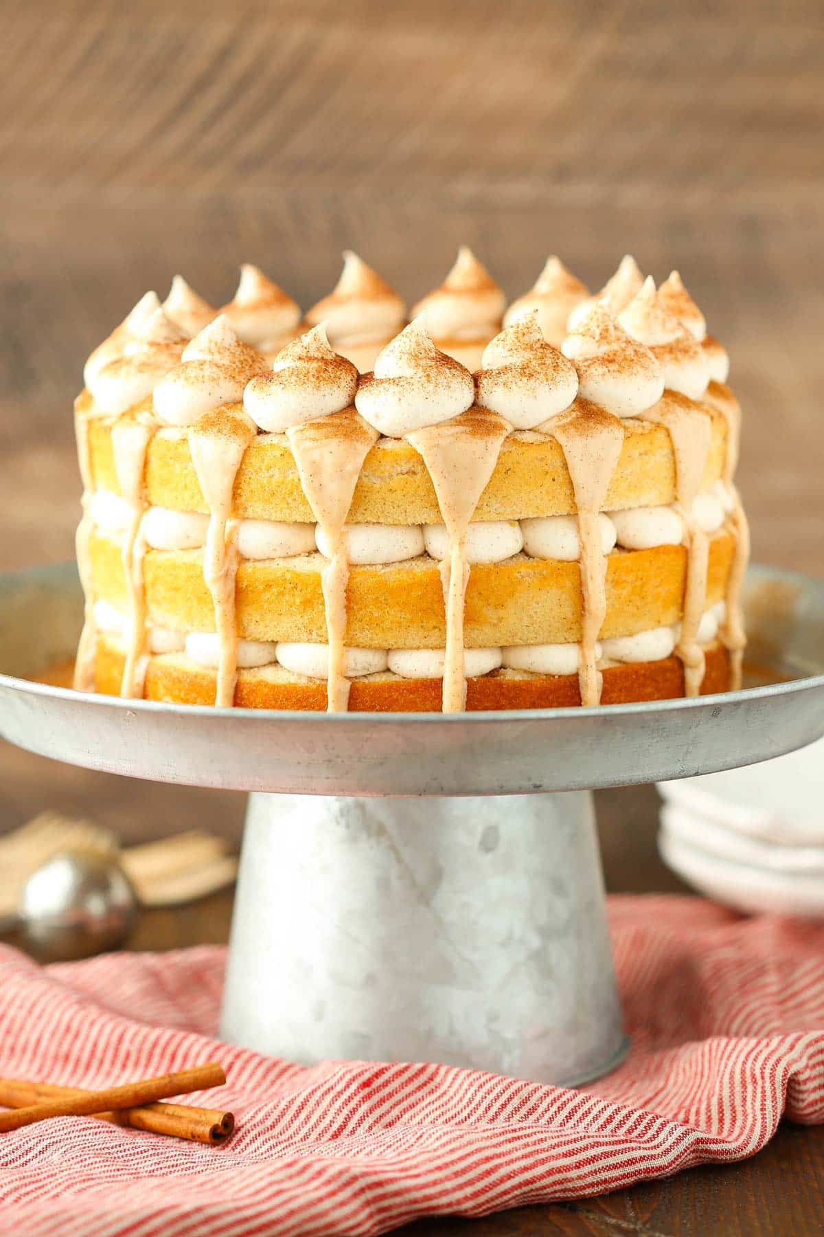 Close up of a cinnamon roll layer cake on a silver cake stand.