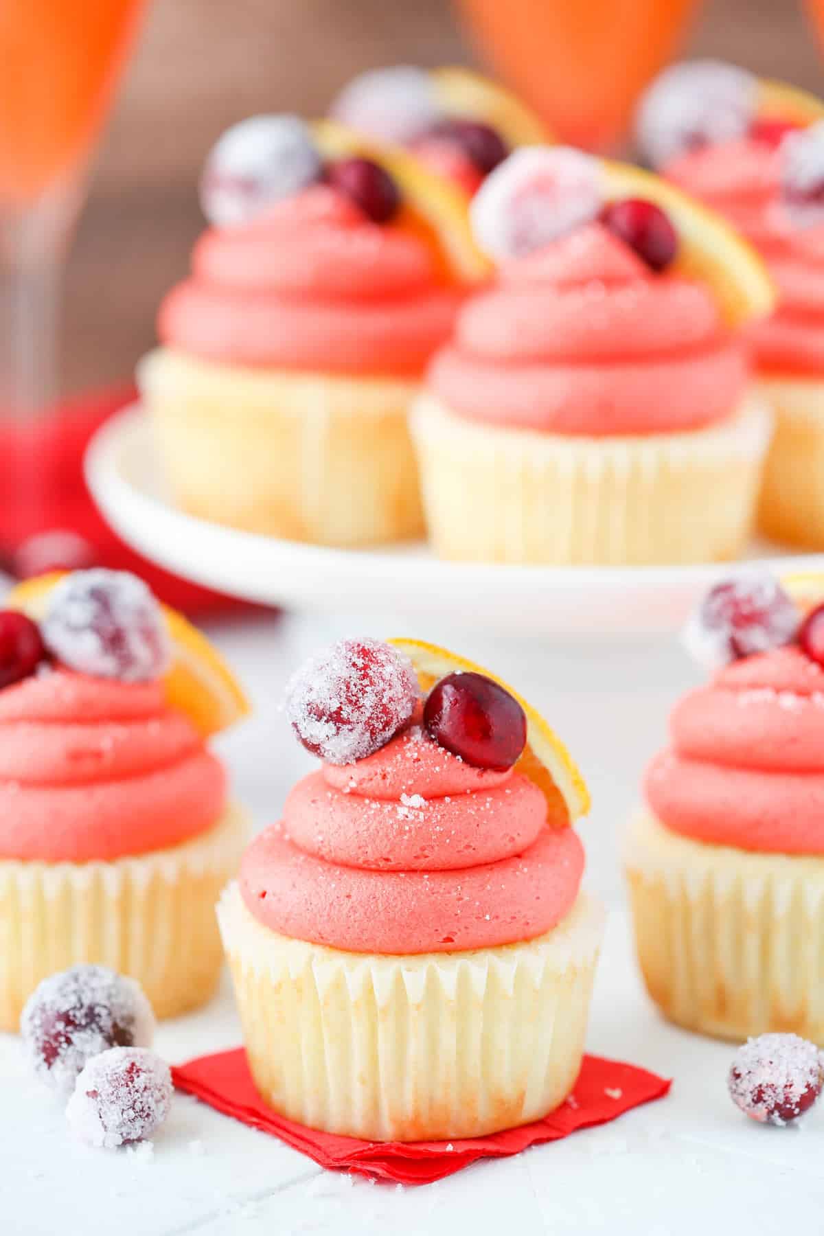 Close up of a cranberry mimosa cupcake with more cupcakes in the background.
