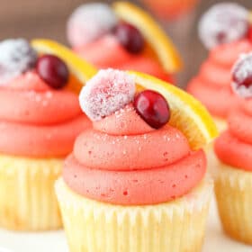Close up of a cranberry mimosa cupcake on a white cake stand.