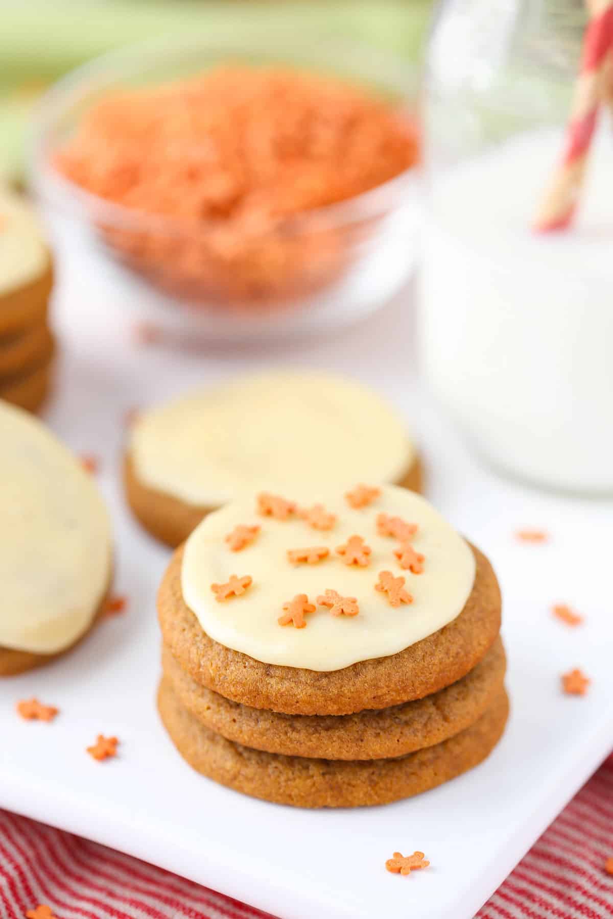 Three gingerbread cookies with eggnog icing on a white cutting board.