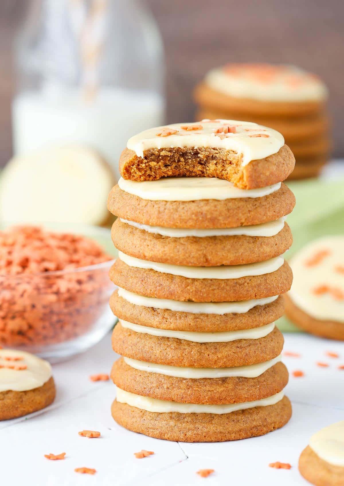 A stack of gingerbread cookies with eggnog icing with a bite removed from top cookie.