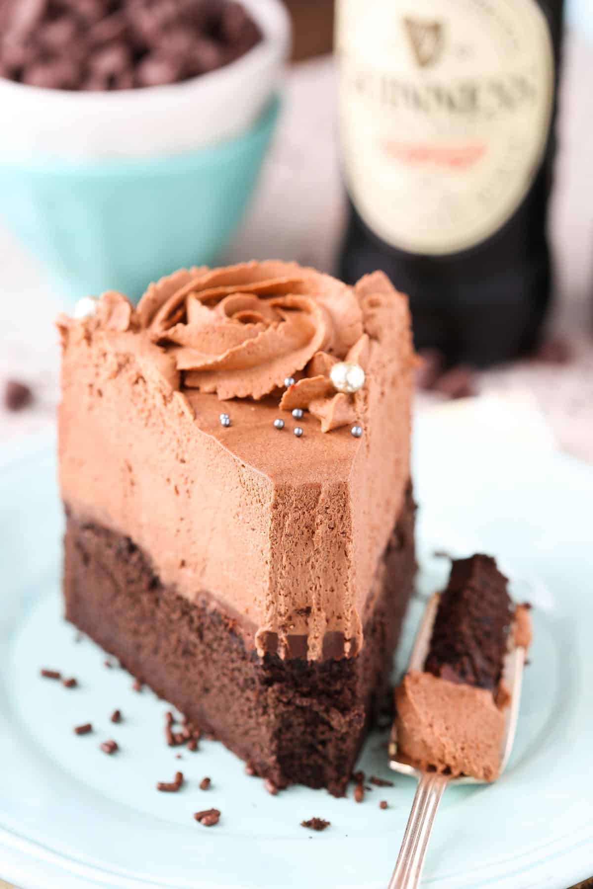 A slice of Guinness chocolate mousse cake on a small blue plate with a bite removed on a fork.