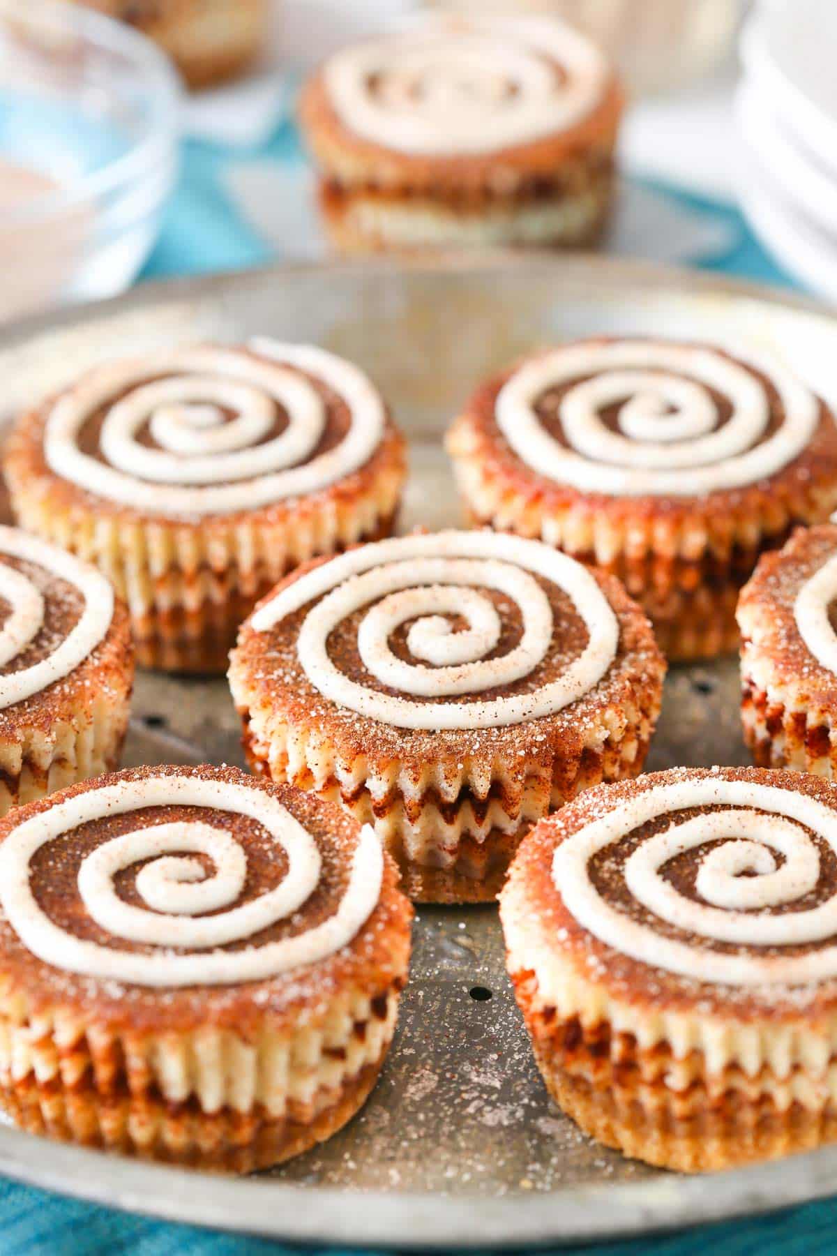Mini cinnamon roll cheesecakes on a silver tray.