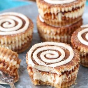 Close up of a mini cinnamon roll cheesecake with a bite removed on a fork.