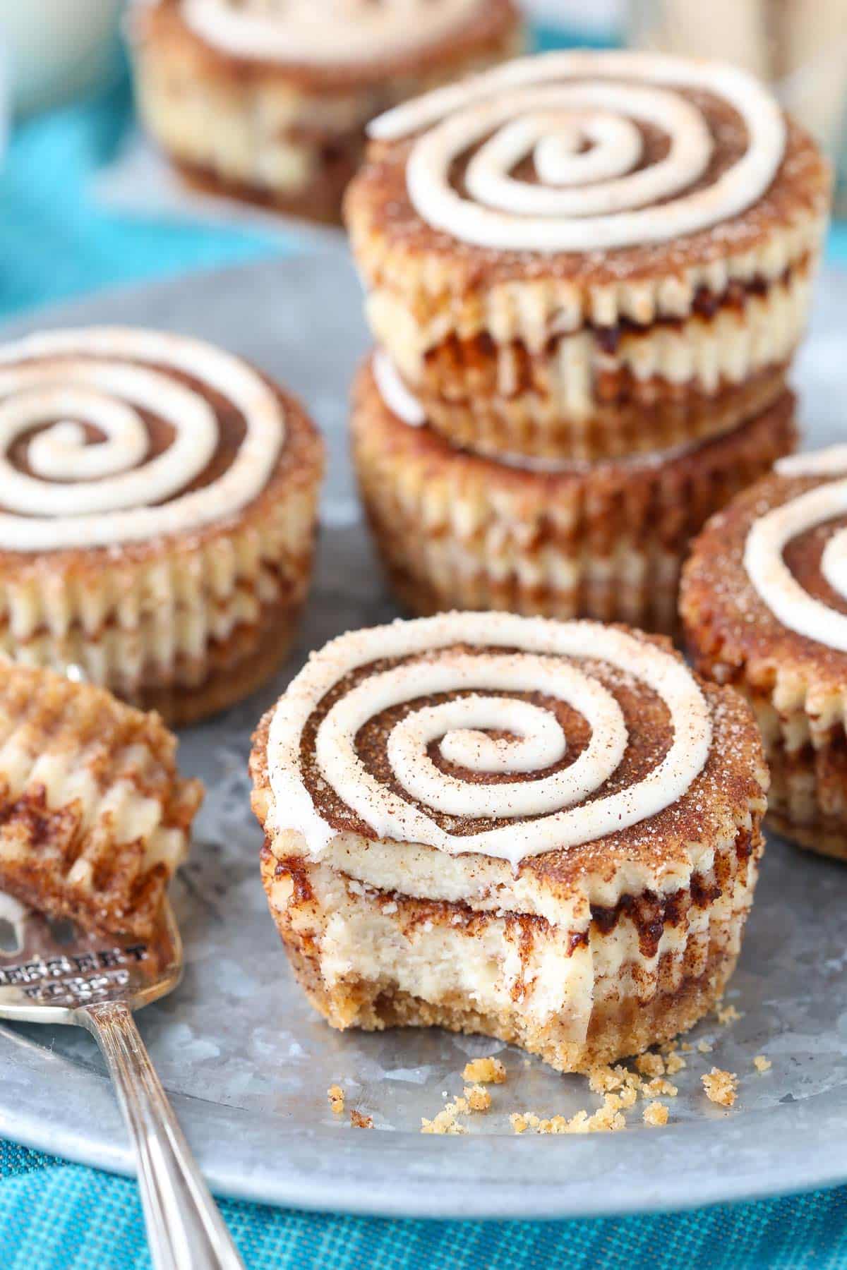 Close up of a mini cinnamon roll cheesecake with a bite removed on a fork.