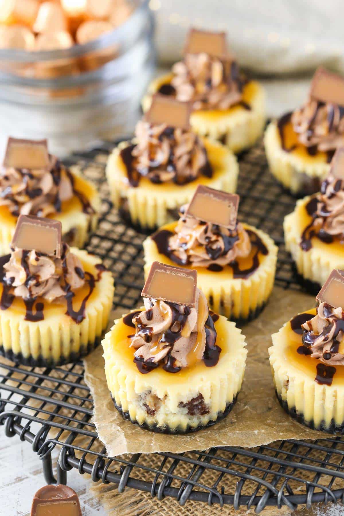Several mini Rolo cheesecakes on a wire rack.