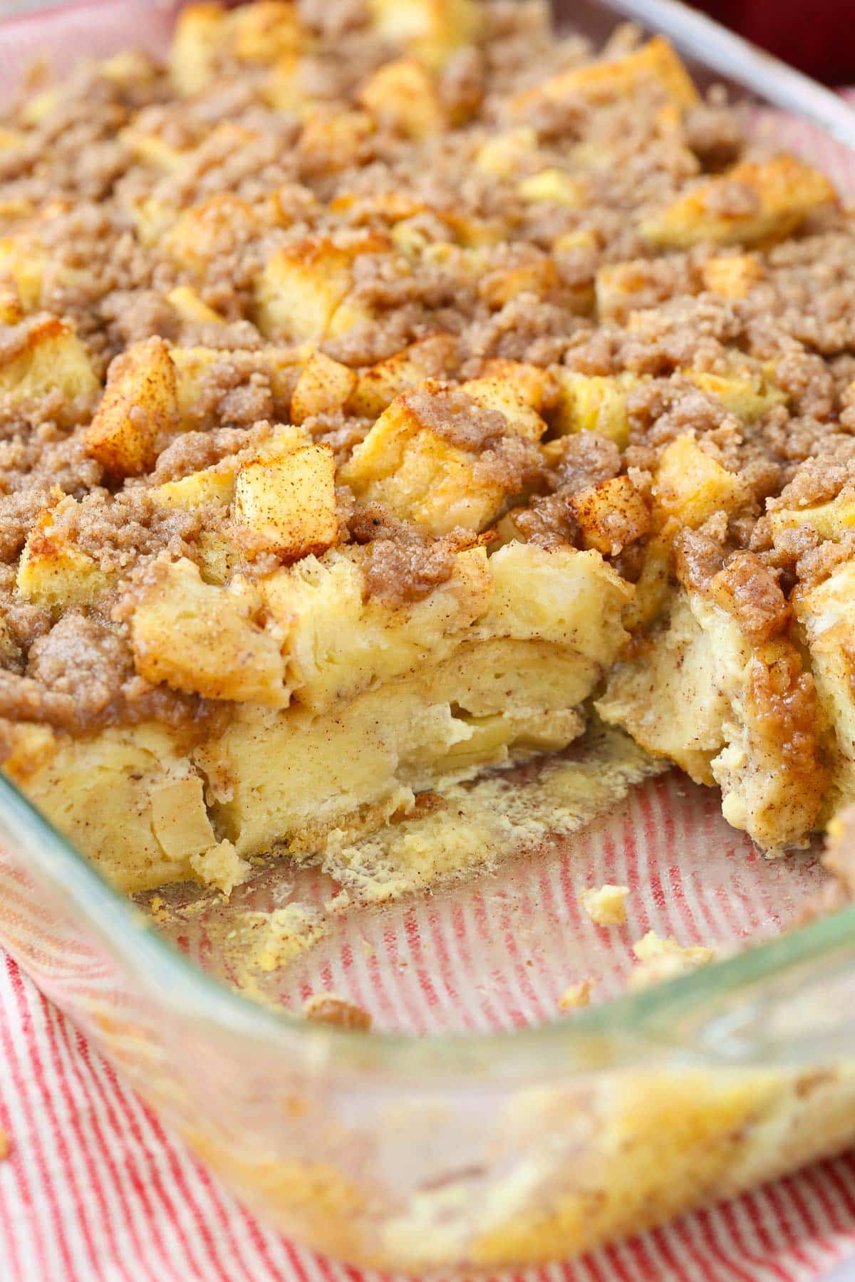 A casserole dish of overnight cinnamon apple French toast casserole with a slice removed.