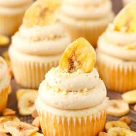 Close up of a peanut butter banana cupcake surrounded by banana chips and peanut butter chips.