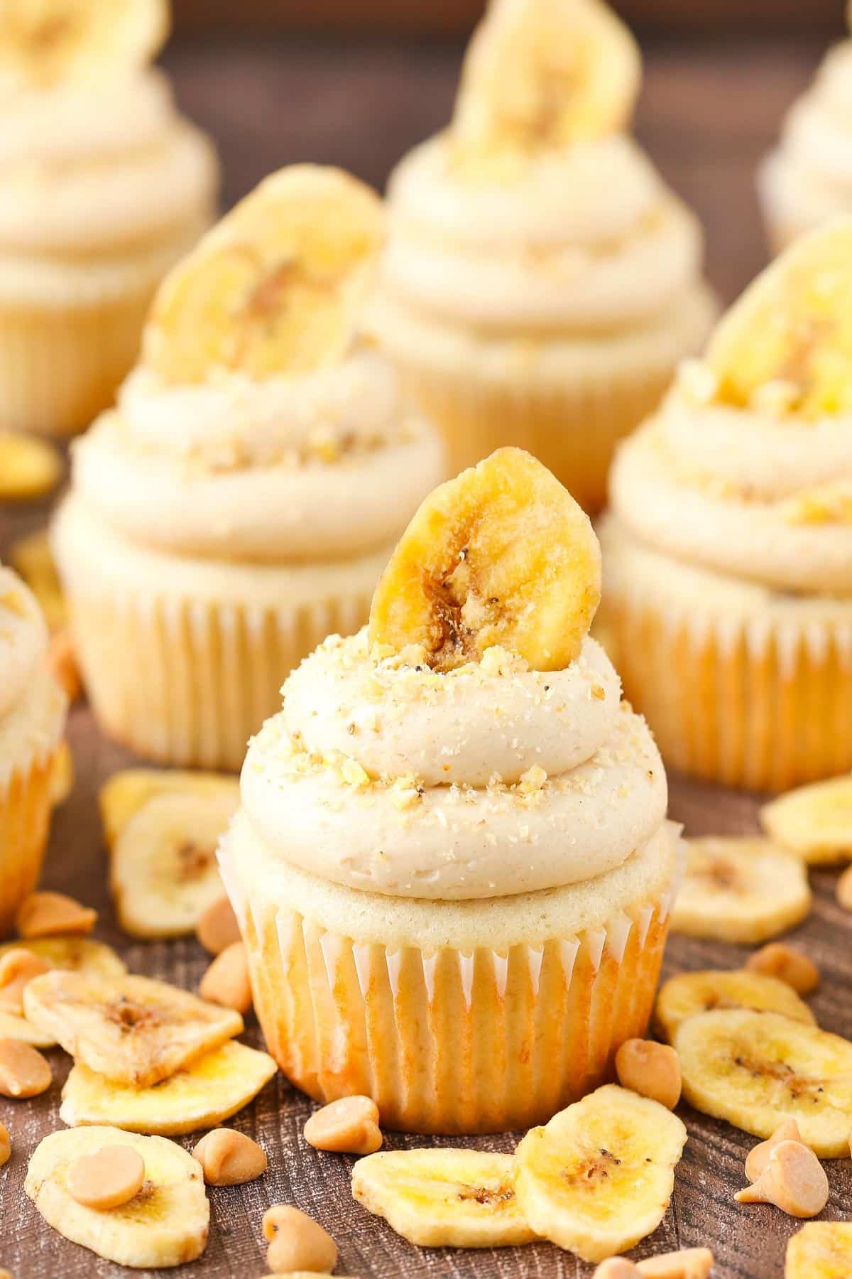 Close up of a peanut butter banana cupcake surrounded by banana chips and peanut butter chips.