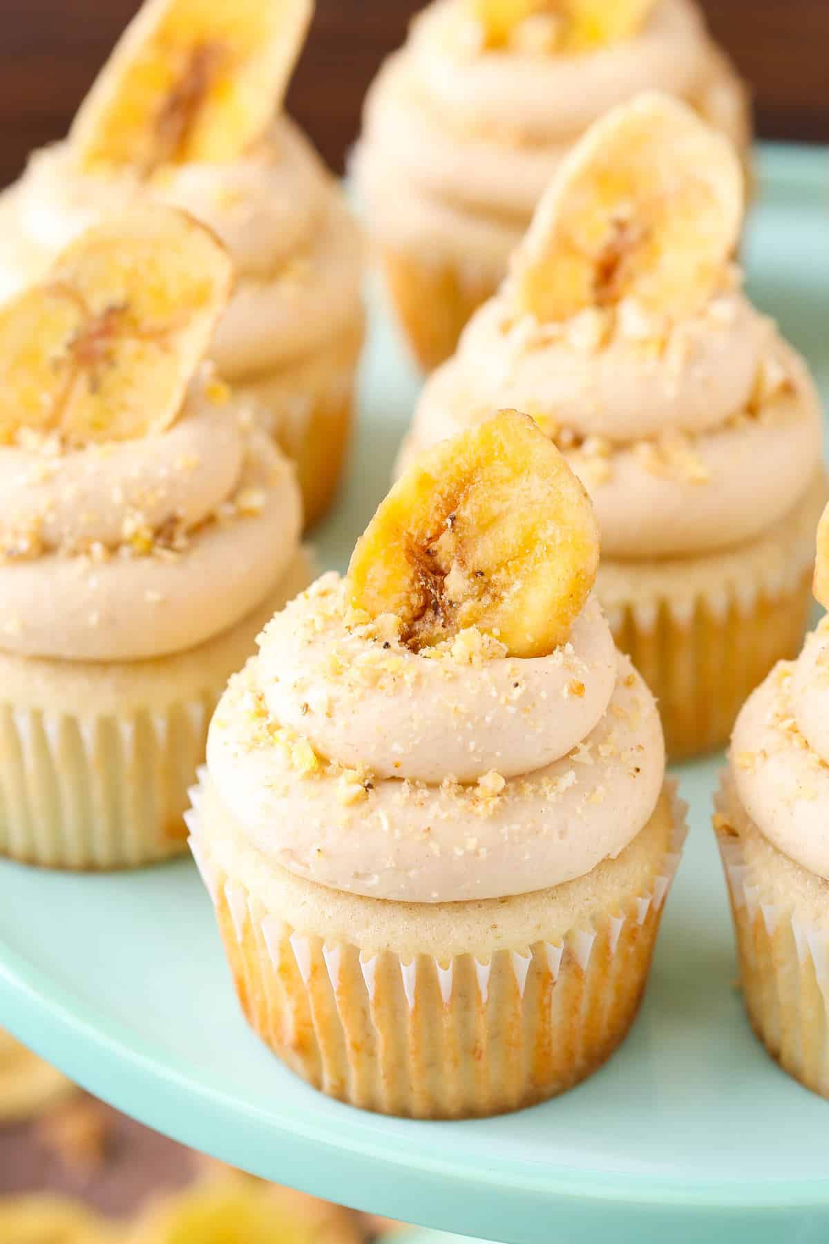 Close up of peanut butter banana cupcakes on a light teal cake stand.