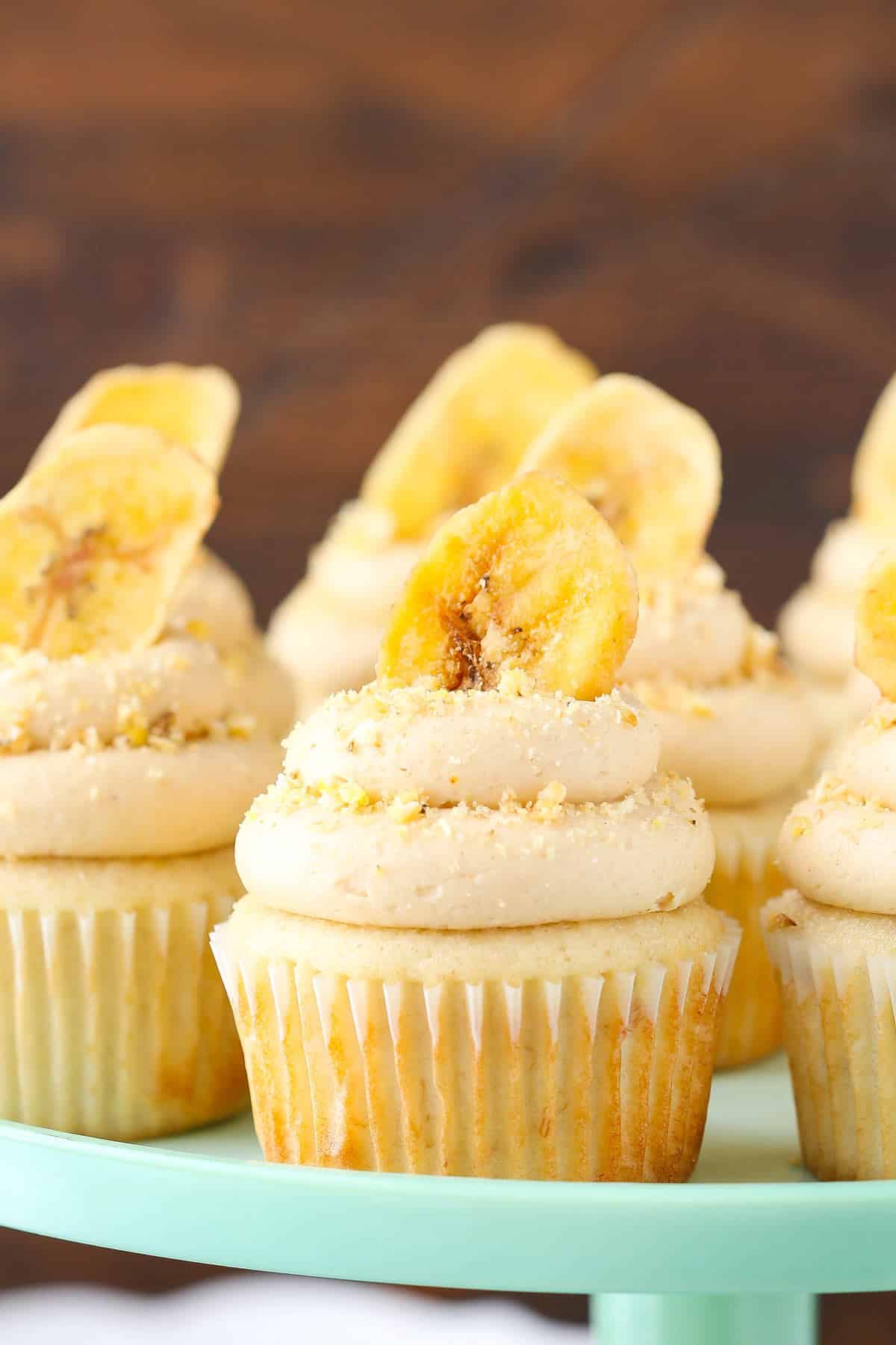 Close up of peanut butter banana cupcakes on a light teal cake stand.