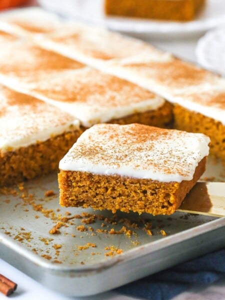 A spatula removing a slice of pumpkin bar from a sheet pan.