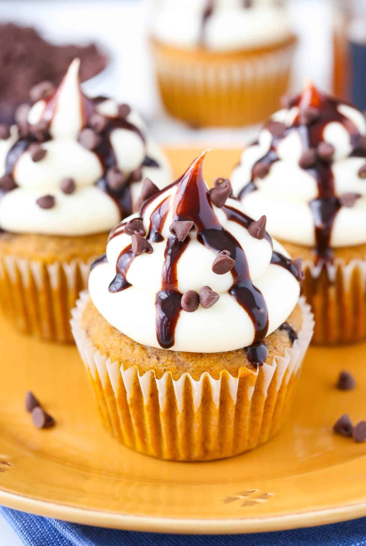 Easy pumpkin spice cupcakes filled with chocolate chips are topped with a homemade cream cheese frosting for the best fall dessert ever! Close up of a pumpkin chocolate chip cupcake.