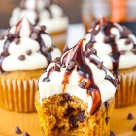 A pumpkin chocolate chip cupcake with a bite taken out of it.