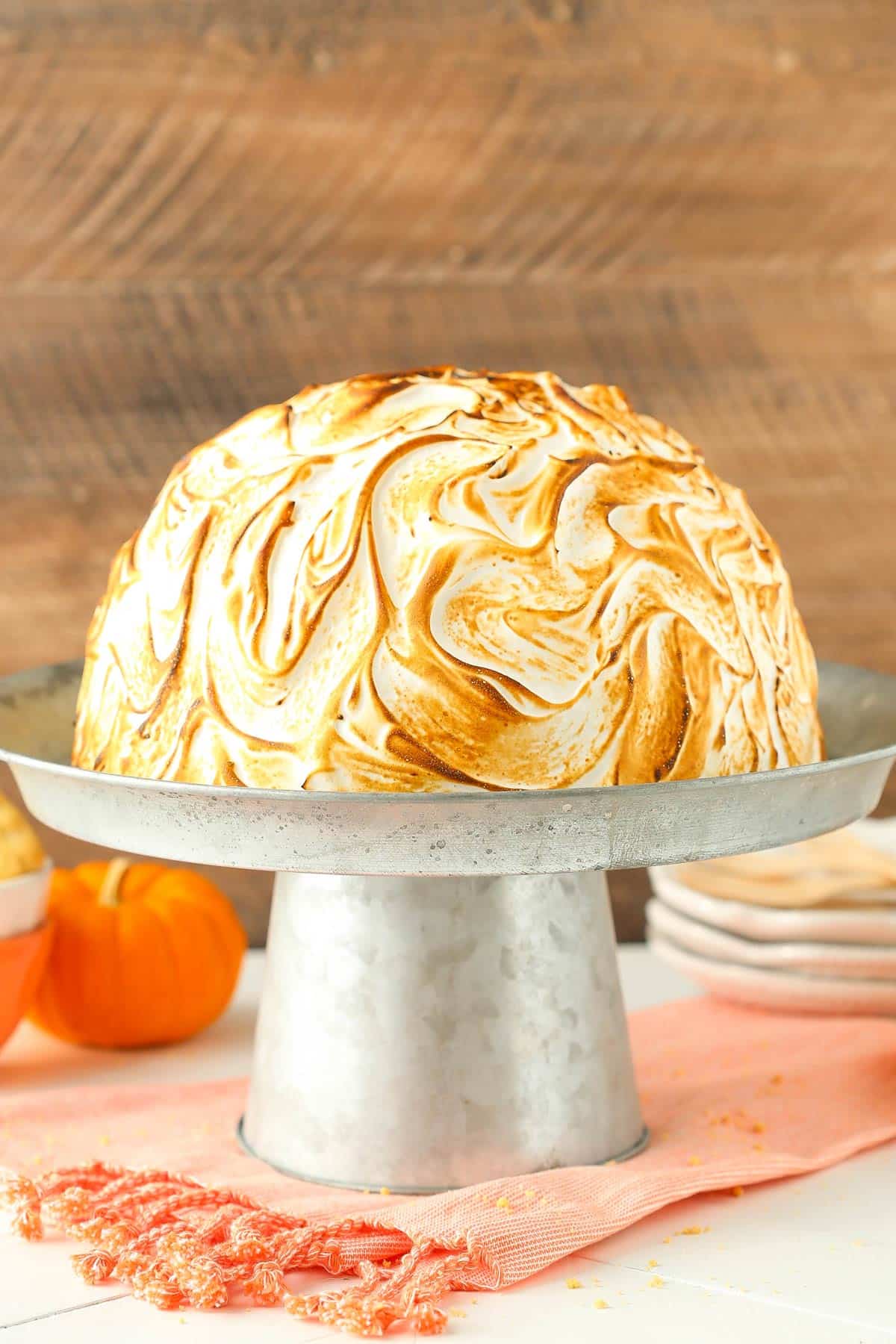 A pumpkin spice baked Alaska on a silver cake stand.