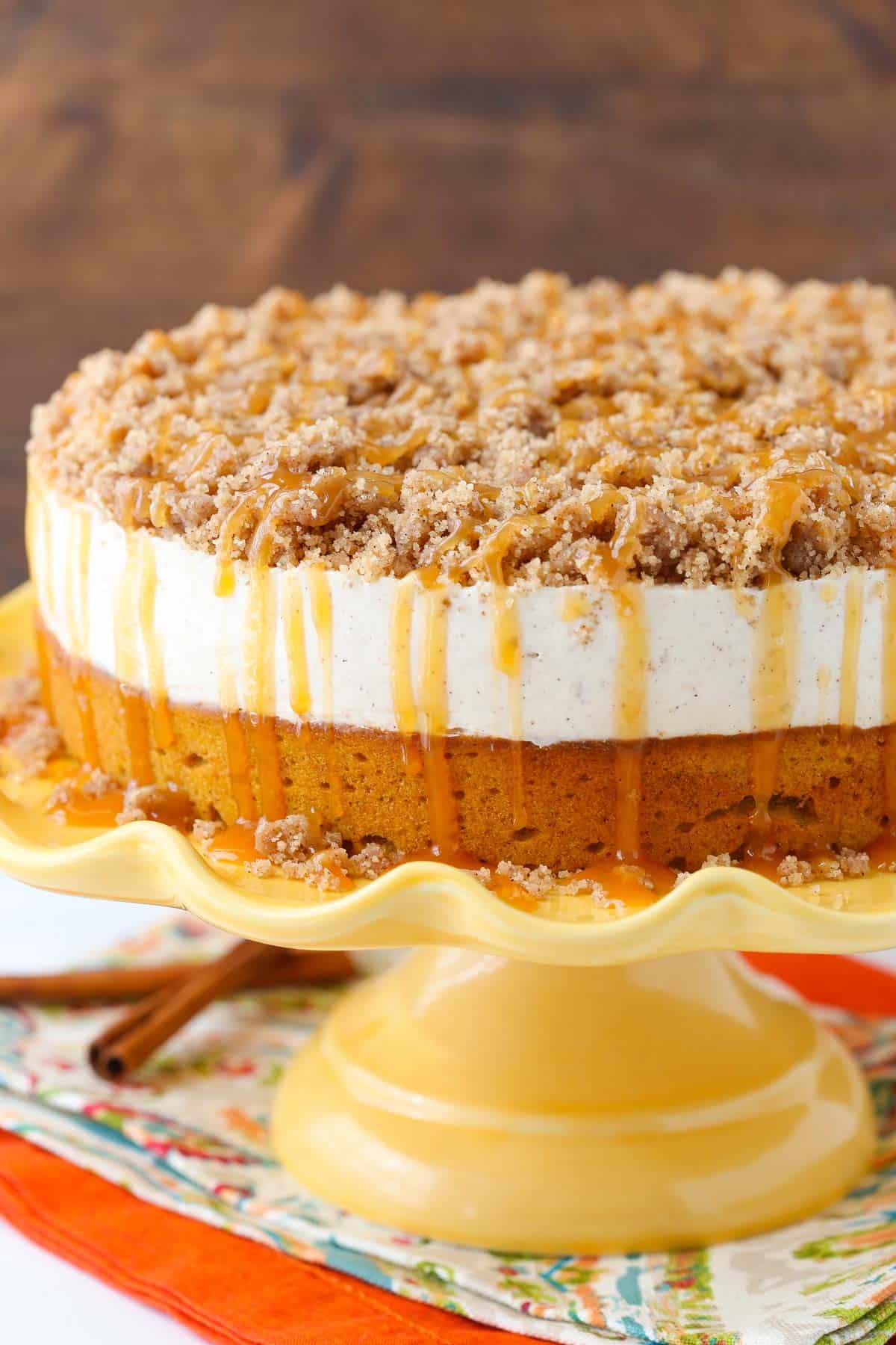 Close up of a caramel pumpkin spice blondie streusel cheesecake on a yellow cake stand.