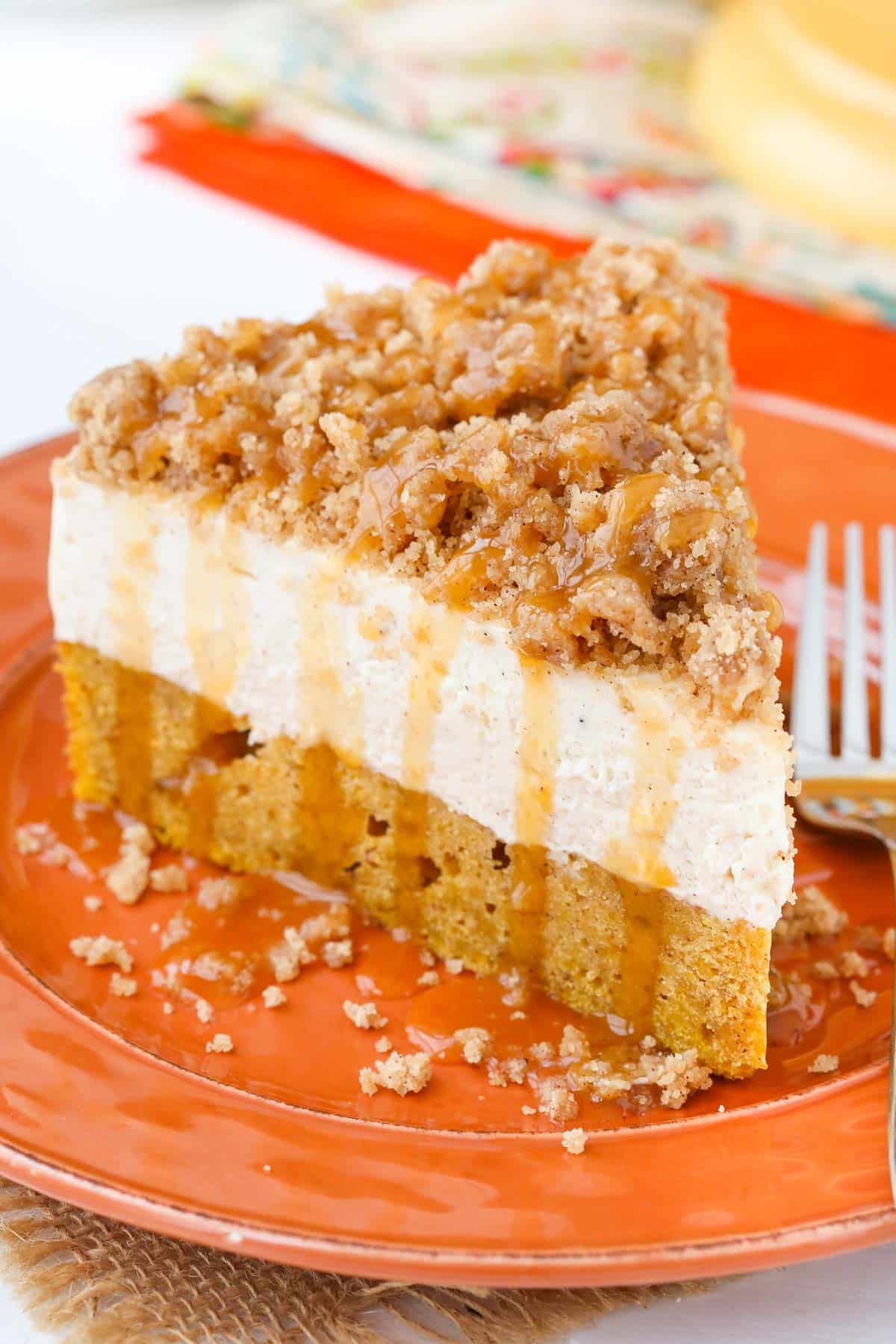 Close up of a slice of caramel pumpkin spice blondie streusel cheesecake on an orange plate.