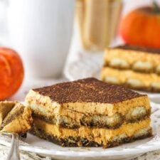 A slice of pumpkin tiramisu on a plate with a bite taken out of it.