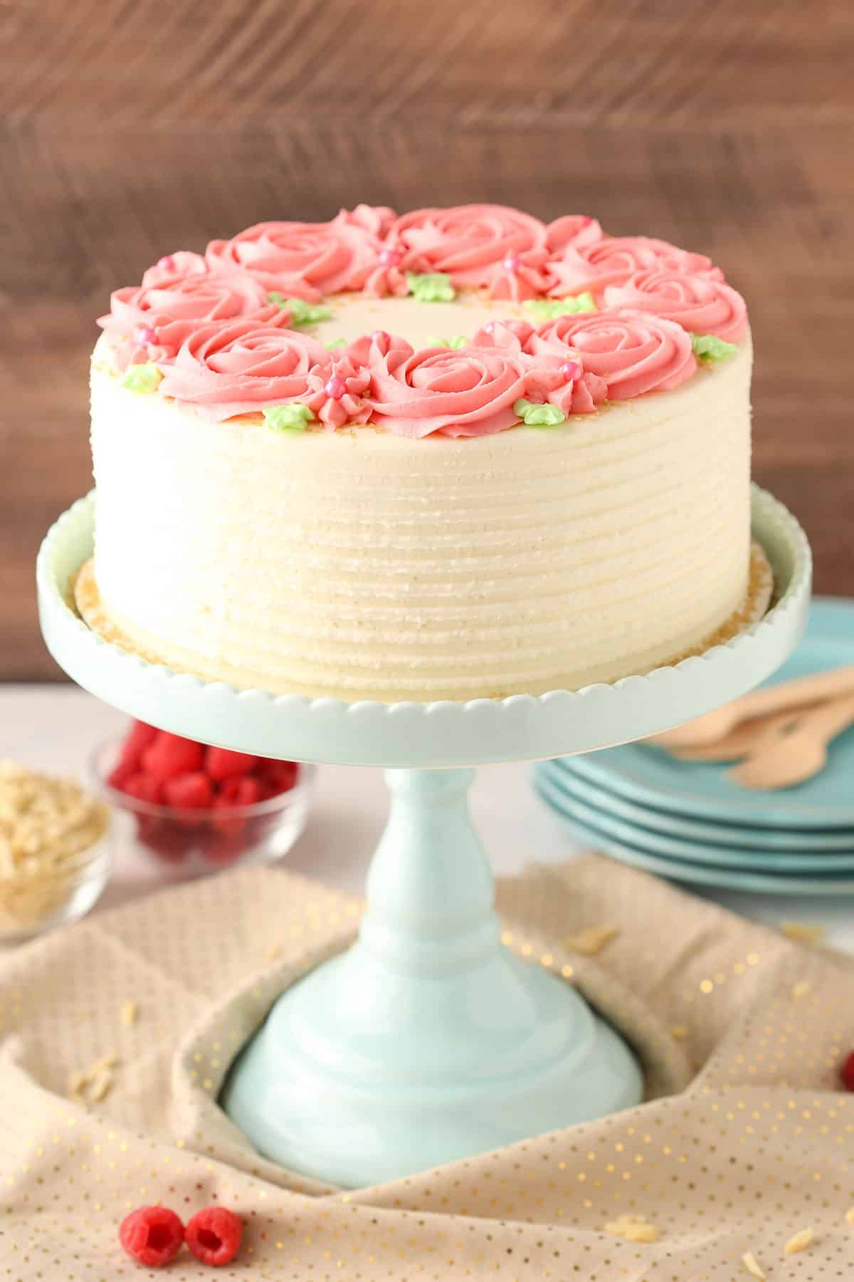 A raspberry almond layer cake on a teal cake stand.