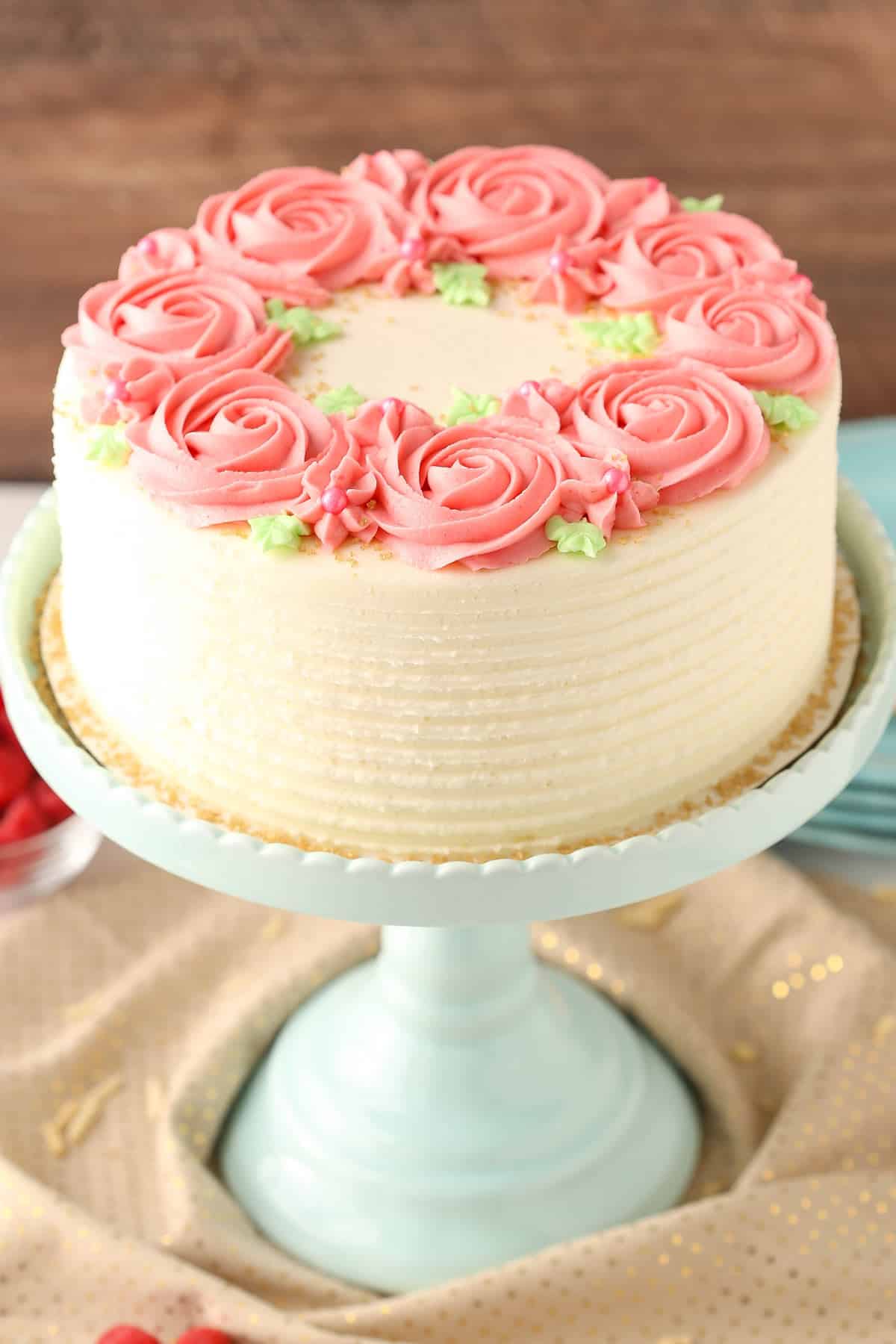 A raspberry almond layer cake on a teal cake stand.