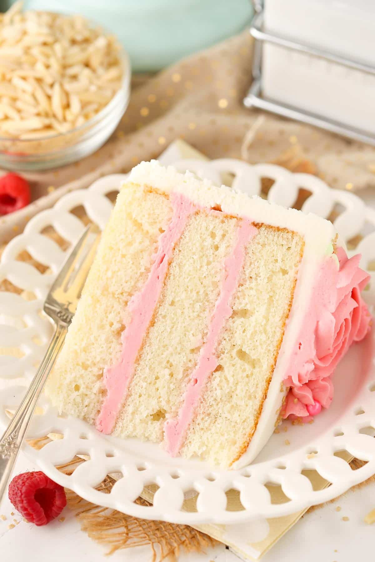 A slice of raspberry almond layer cake on a white plate.