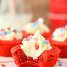 Close up of a red velvet cheesecake cookie cup with a bite taken out of it.