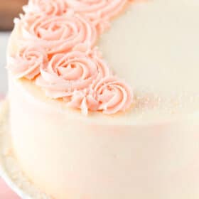 Close up of a rose water vanilla layer cake on a white cake plate.