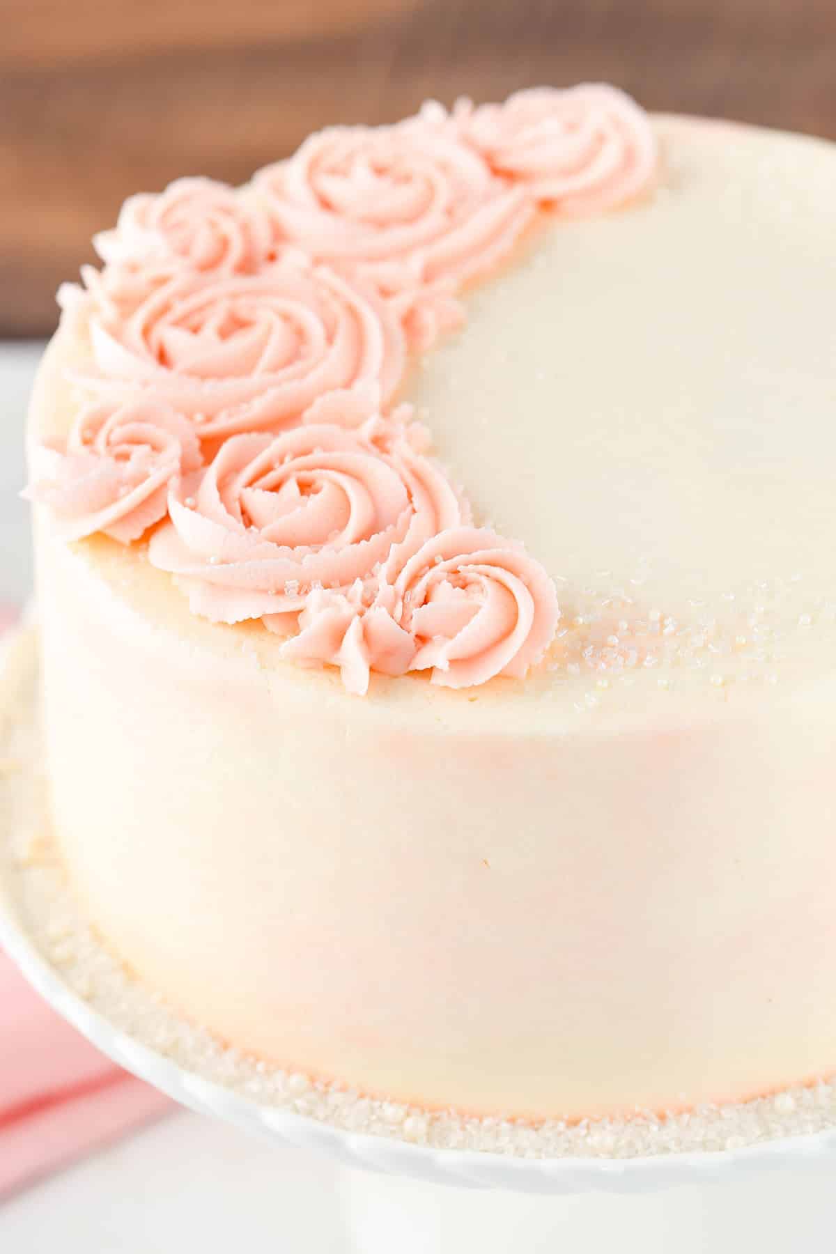 Close up of a rose water vanilla layer cake on a white cake plate.