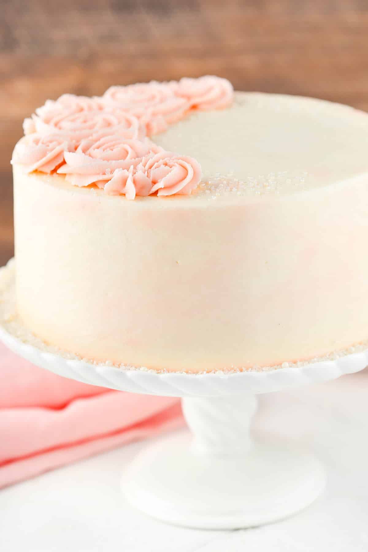 Close up of a rose water vanilla layer cake on a white cake stand.