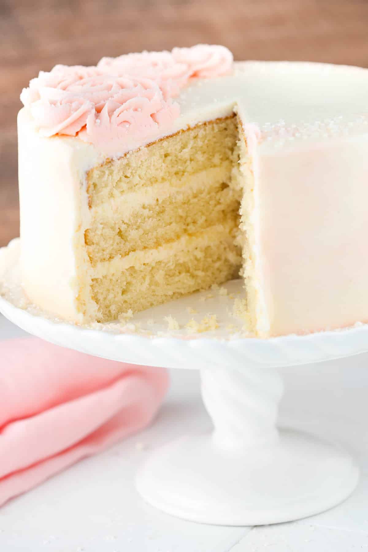 A rose water vanilla layer cake with a slice removed to show interior layers.