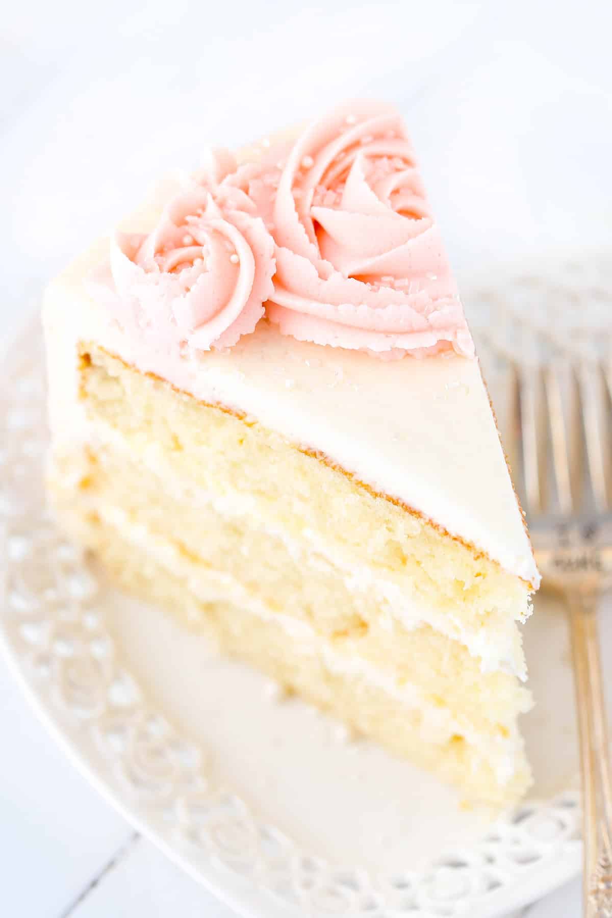 Top view of a slice of rose water vanilla layer cake on a white plate.
