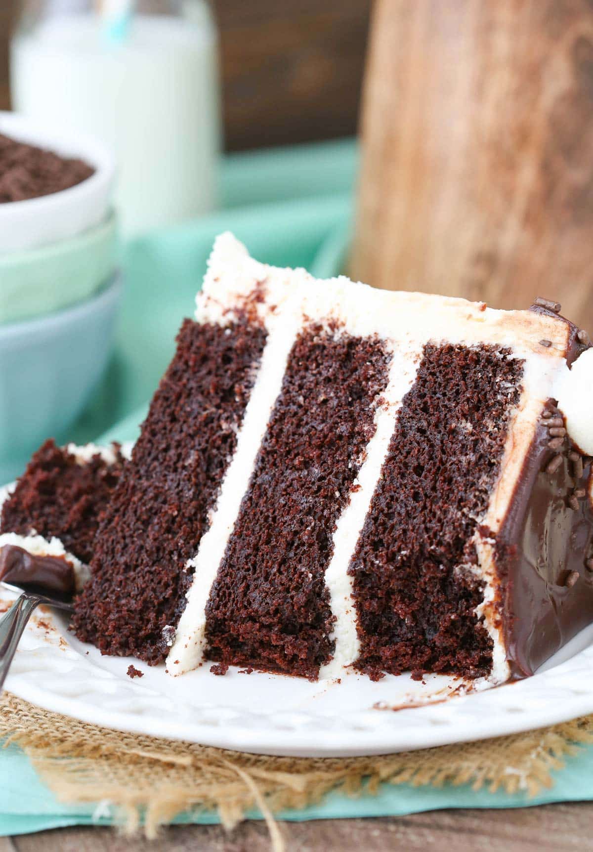 A slice of Baileys chocolate cake with a few bites removed on a white plate.