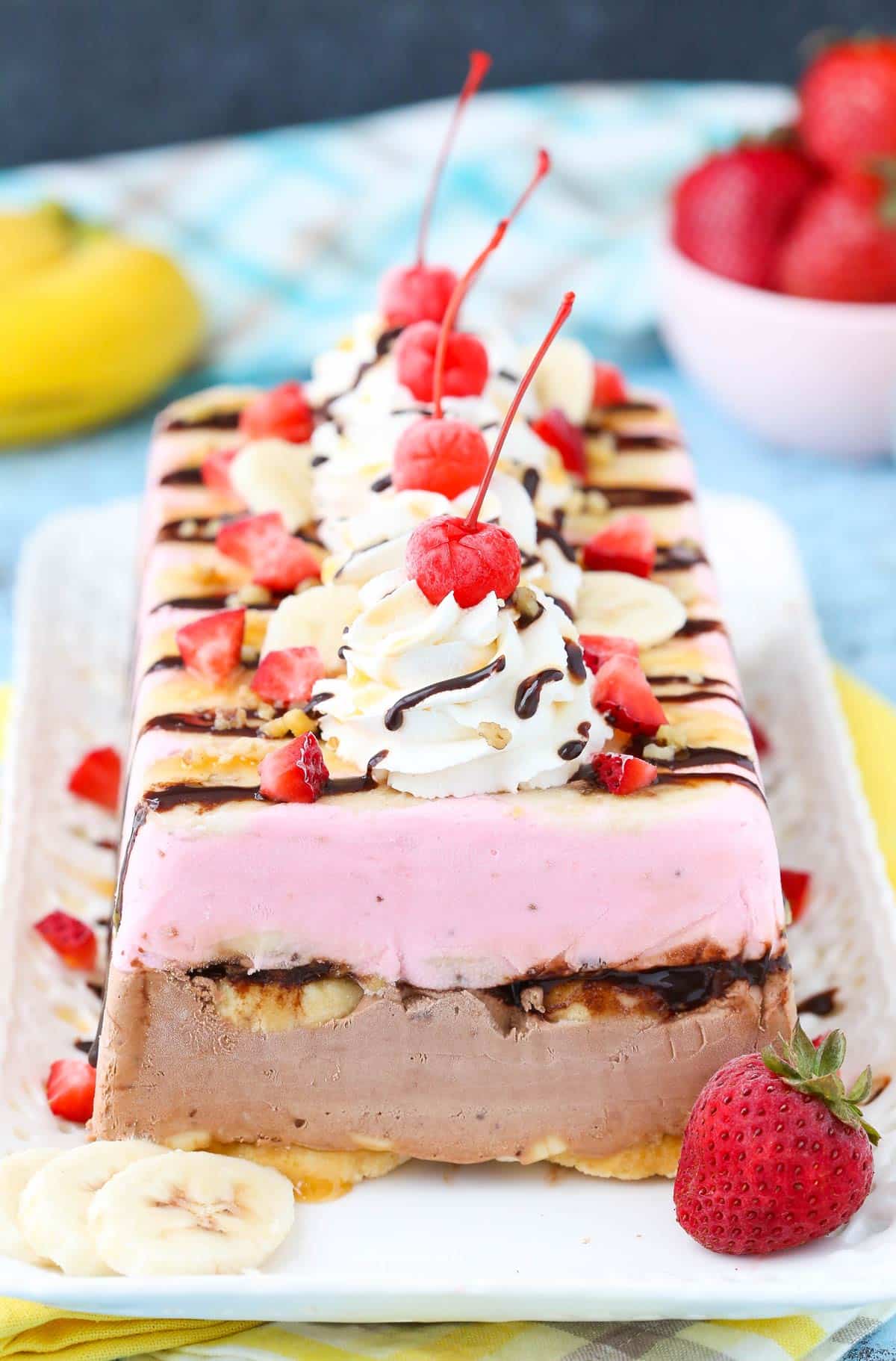 A banana split ice cream cake loaf on a white tray.