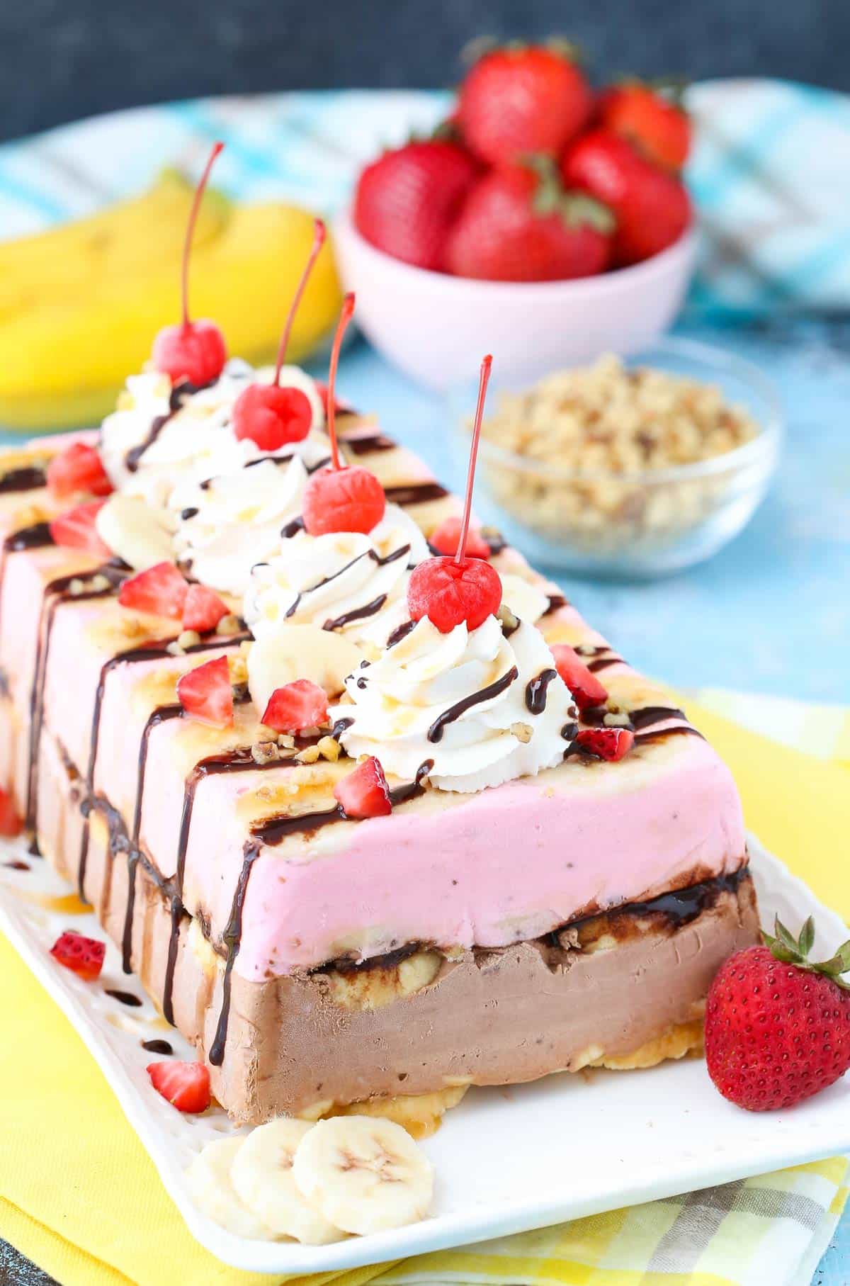 Side view of a banana split ice cream cake loaf on a white tray.
