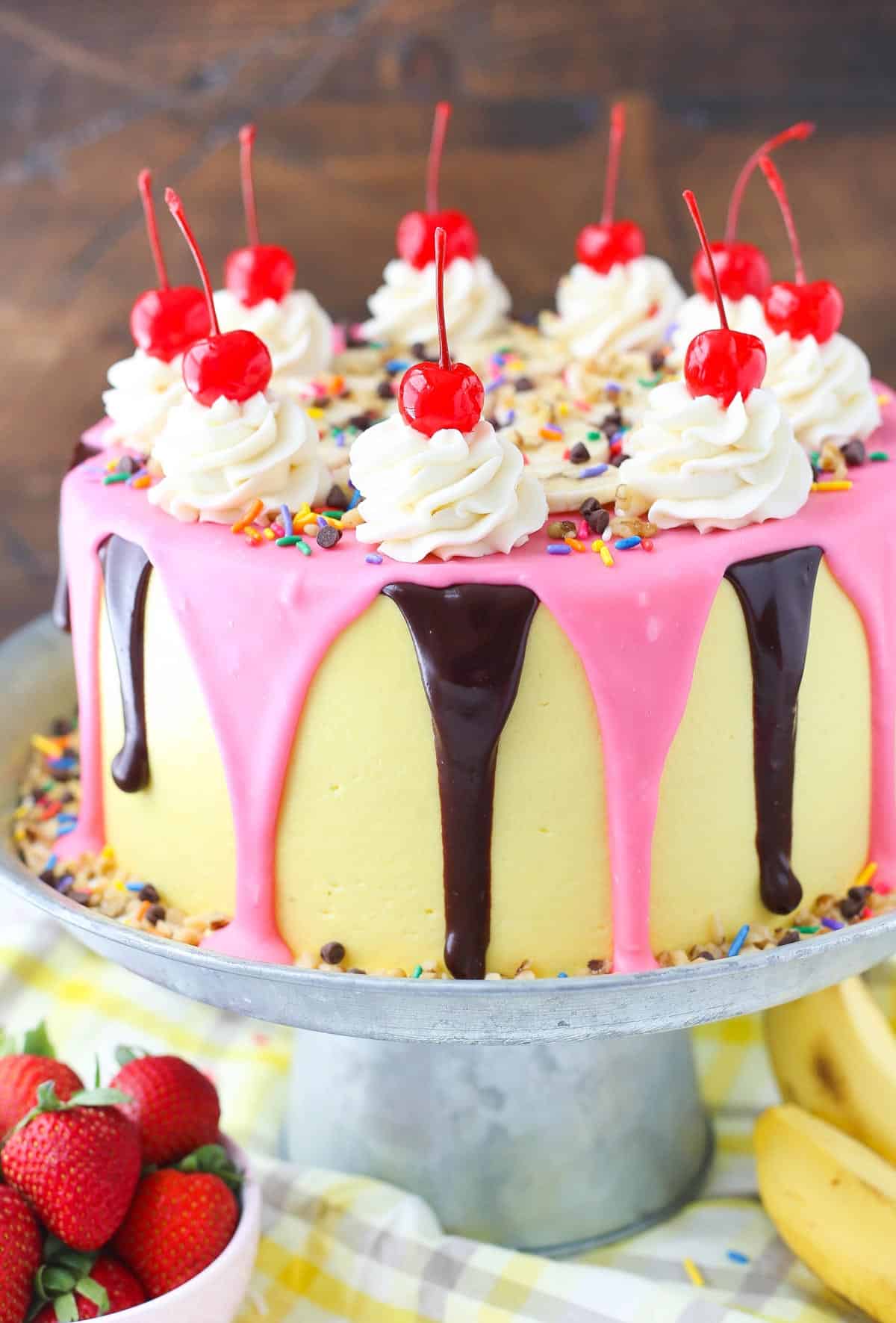 Close up of the side of a banana split layer cake on a silver cake stand.